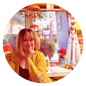 Jill sits in her bright, cheerful craft studio, smiling at the camera.