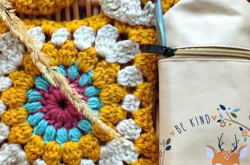 granny square in fall colors with crochet hook case with deer drawing and words "be kind."