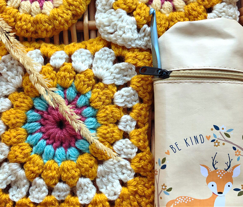 granny square in fall colors with crochet hook case with deer drawing and words "be kind."