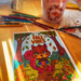 An autumn display decorates a yellow kitchen table. Colored pencils in fall hues surround a coloring page of a cute squirrel in the forest holding a chestnut with the words "Fall Vibes" above his head.